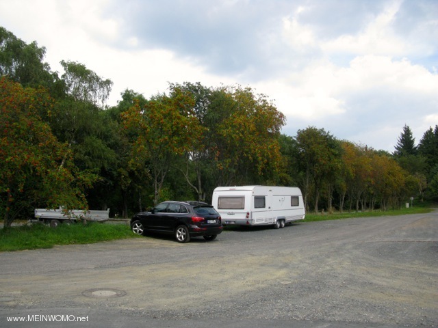 Parking lot with gravel surface, in addition to various waste containers, including glass