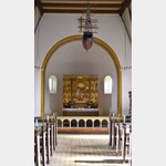 Hier ist die Innenansicht der Gudhjem Kirche auf dem Bild zu sehen mit der dreigeteilten Altartafel und dem Kirchenschiff unter der Decke