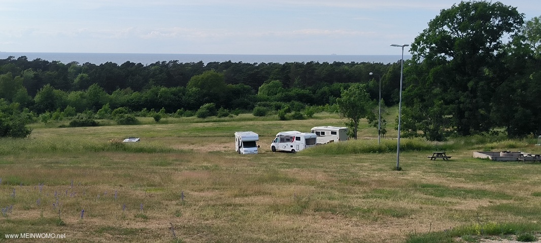 Utsikt frn sanitetsbyggnaden ver det oskiftade utrymmet och stersjn, skogen och stersjn bakom  ...