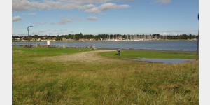 Blick von der Zufahrtsstrae ber die kleine Parkflche vor dem Hafengelnde von Sundstrup hinber zum Yachthafen von Virksund.