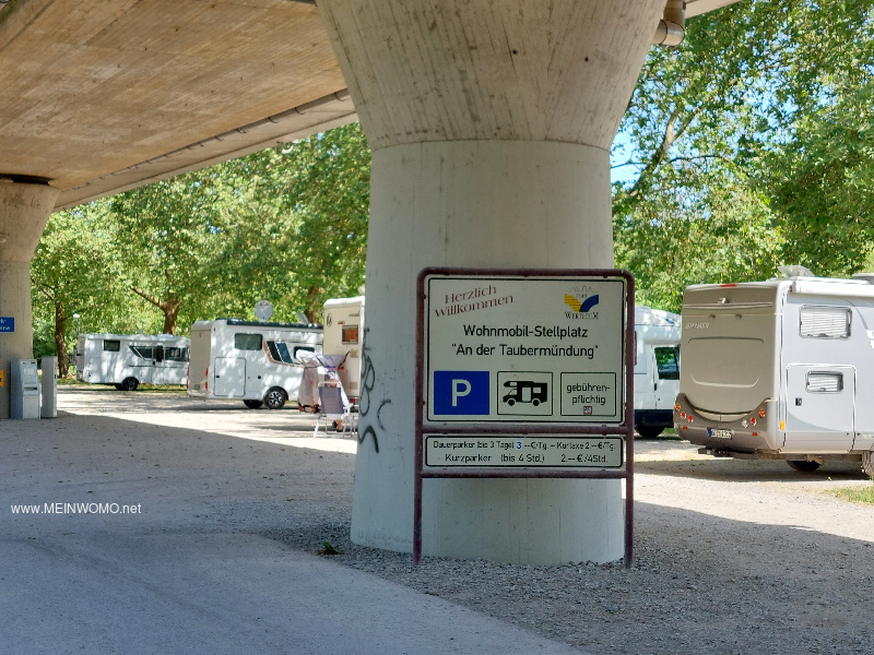 The parking spaces are located under a busy main road