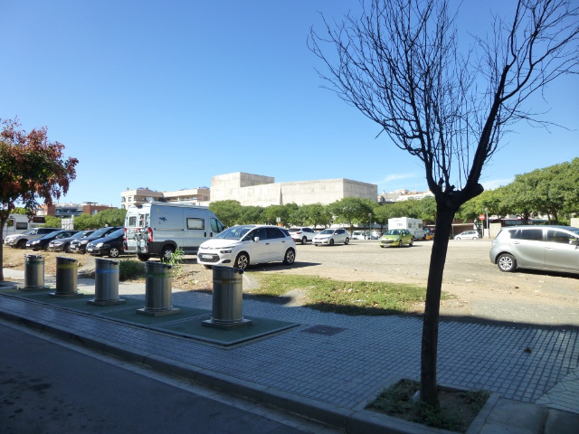 Parkplatz mit Mlltonnen im Vordergrund.